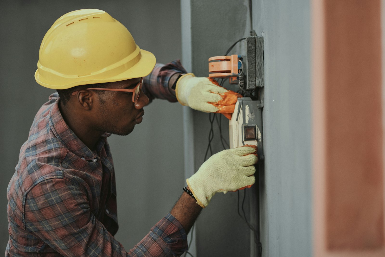 Electrician wiring a junction box, wearing a hard hat
