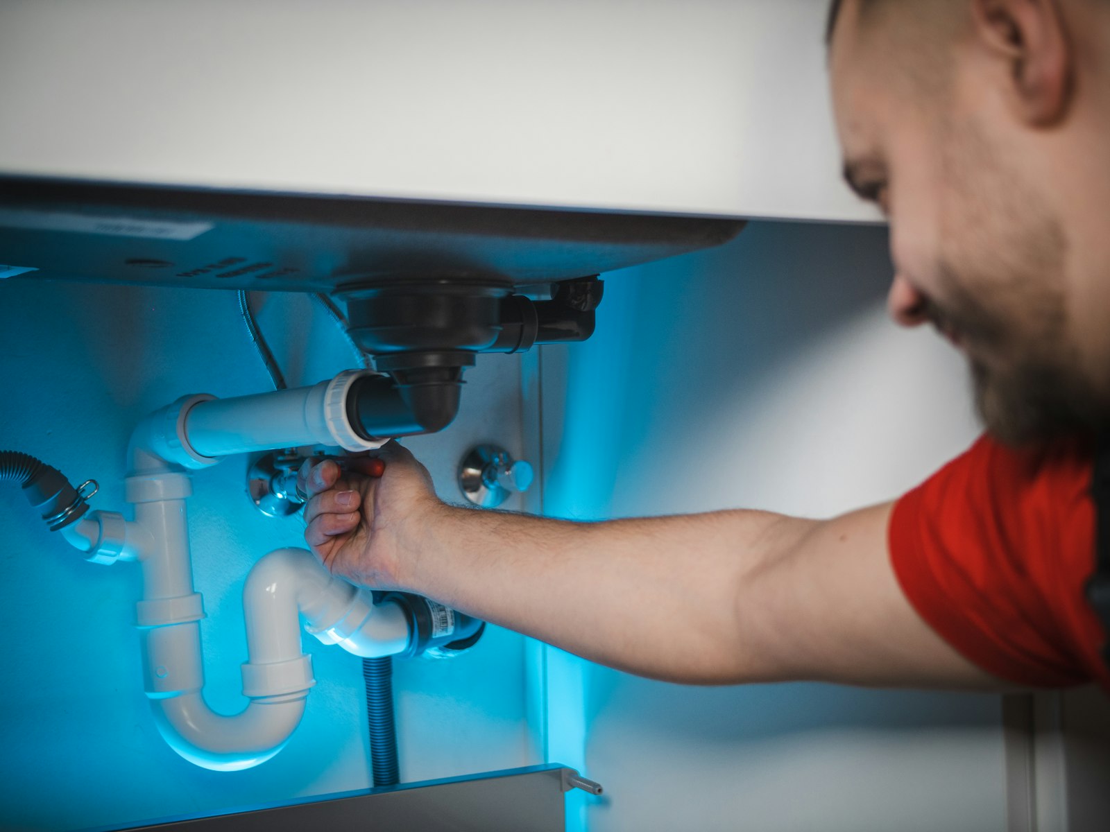 Plumber repairing pipework under a sink